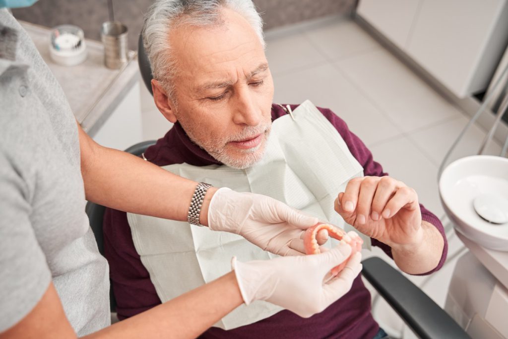 Person in dental chair looking at dentures