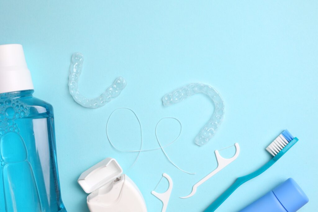 Transparent plastic dental aligners and care products on a colored background. High quality photo